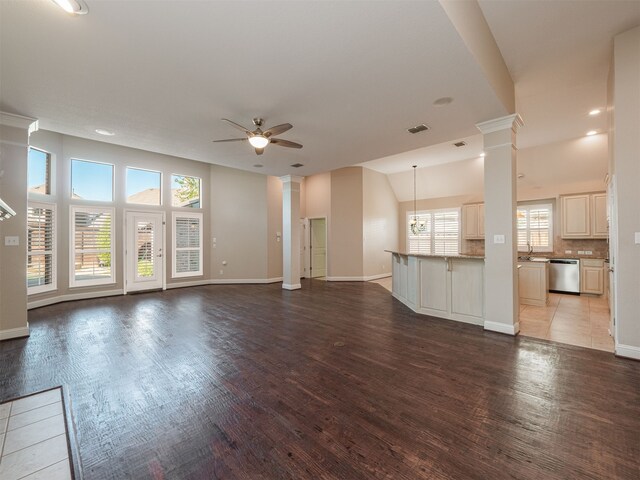 unfurnished living room with ceiling fan, light wood-type flooring, sink, and ornate columns