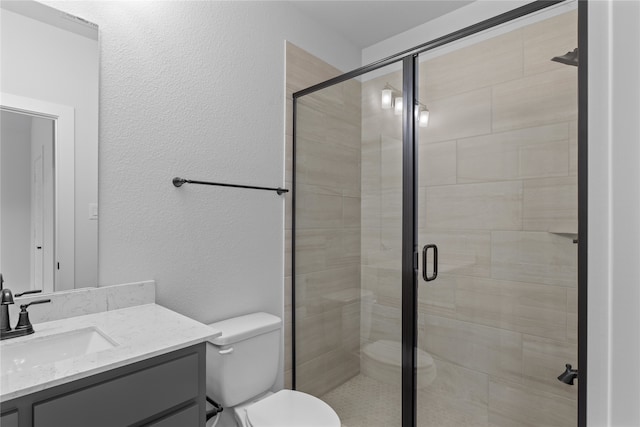 bathroom featuring a shower with door, vanity, and toilet