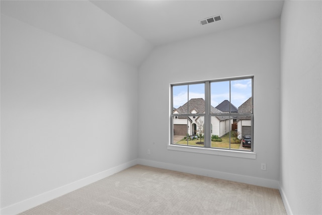 carpeted spare room featuring lofted ceiling