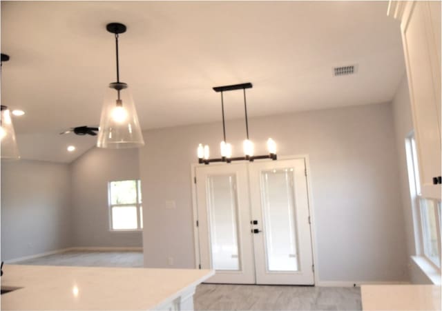 kitchen with french doors, vaulted ceiling, light carpet, and pendant lighting