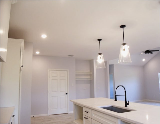 kitchen featuring sink, white cabinetry, decorative light fixtures, and light wood-type flooring