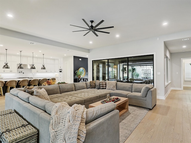 living room featuring light wood-type flooring and ceiling fan