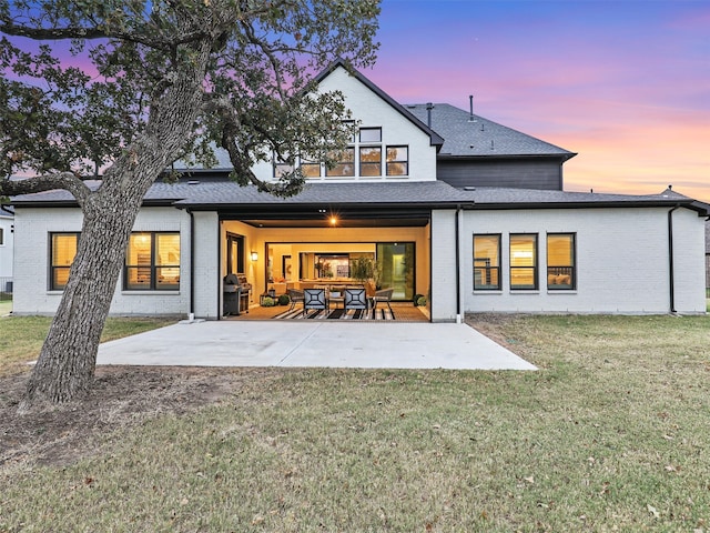 back house at dusk with a patio area and a yard