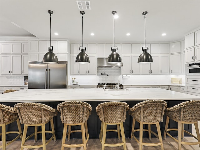 kitchen with a large island, white cabinetry, stainless steel appliances, and a kitchen breakfast bar