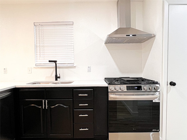 kitchen featuring stainless steel gas range, sink, dishwasher, and wall chimney exhaust hood