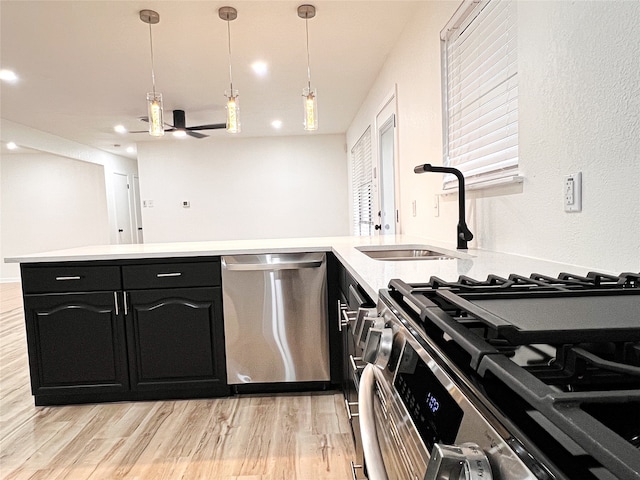 kitchen with light hardwood / wood-style flooring, stainless steel appliances, sink, and pendant lighting