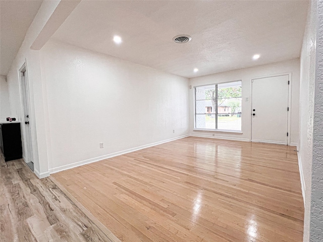 unfurnished room with light hardwood / wood-style floors and a textured ceiling