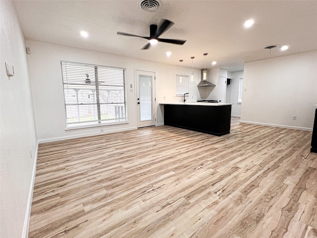 unfurnished living room with sink, light wood-type flooring, and ceiling fan