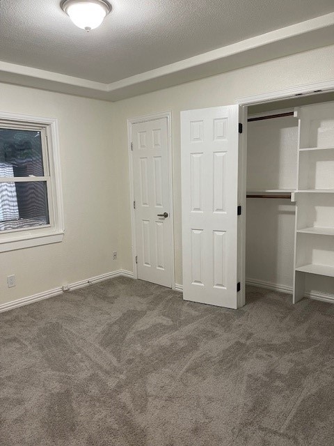 unfurnished bedroom with dark carpet and a textured ceiling