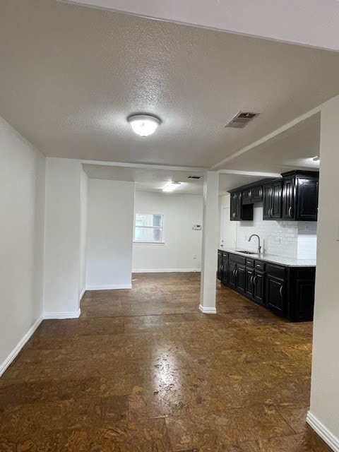 basement featuring a textured ceiling and sink