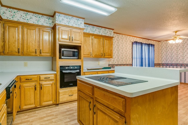 kitchen with crown molding, black appliances, a textured ceiling, a kitchen island, and light wood-type flooring