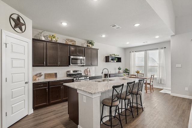 kitchen featuring sink, appliances with stainless steel finishes, dark wood-type flooring, and a kitchen island with sink