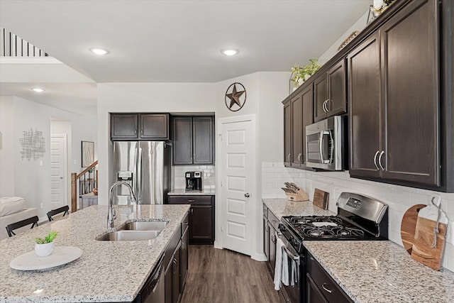 kitchen with a breakfast bar area, light stone countertops, dark hardwood / wood-style floors, sink, and stainless steel appliances