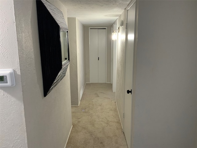 hall with light carpet and a textured ceiling