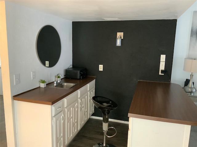 interior space featuring dark wood-type flooring, sink, and white cabinets