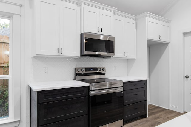 kitchen featuring crown molding, dark hardwood / wood-style floors, decorative backsplash, appliances with stainless steel finishes, and white cabinetry