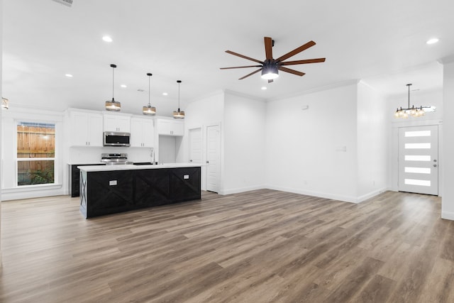 kitchen featuring hardwood / wood-style floors, a center island with sink, crown molding, appliances with stainless steel finishes, and white cabinetry