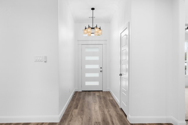 foyer with hardwood / wood-style flooring, a chandelier, and ornamental molding