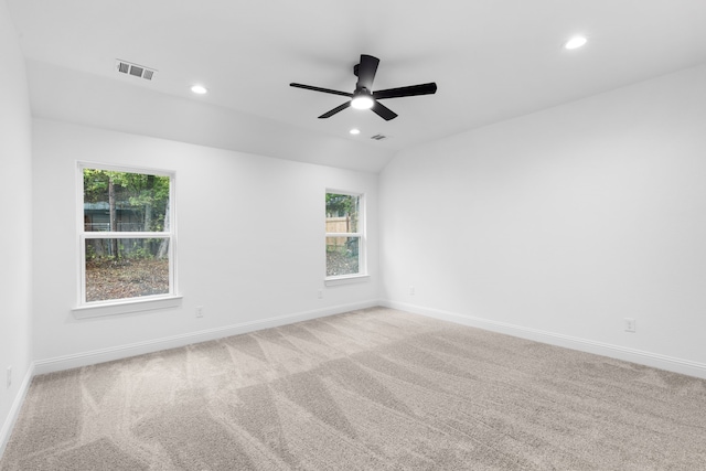 carpeted spare room featuring plenty of natural light, ceiling fan, and lofted ceiling