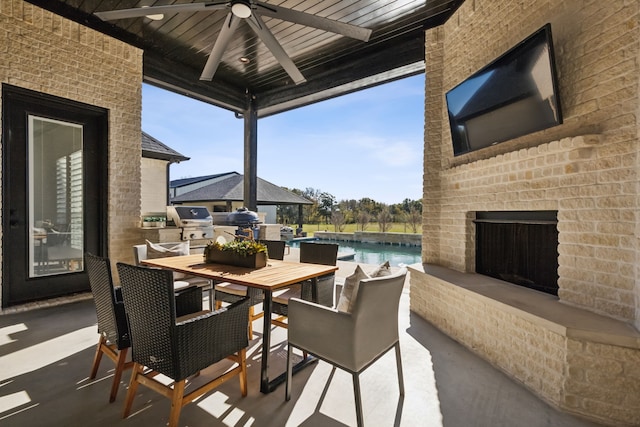 view of patio / terrace with grilling area, ceiling fan, an outdoor kitchen, and an outdoor brick fireplace