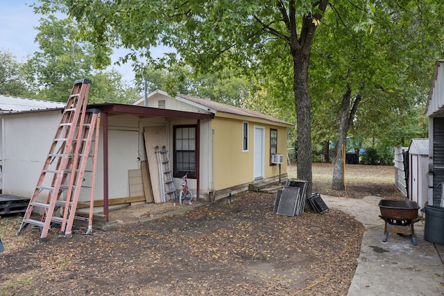 back of house with a storage shed