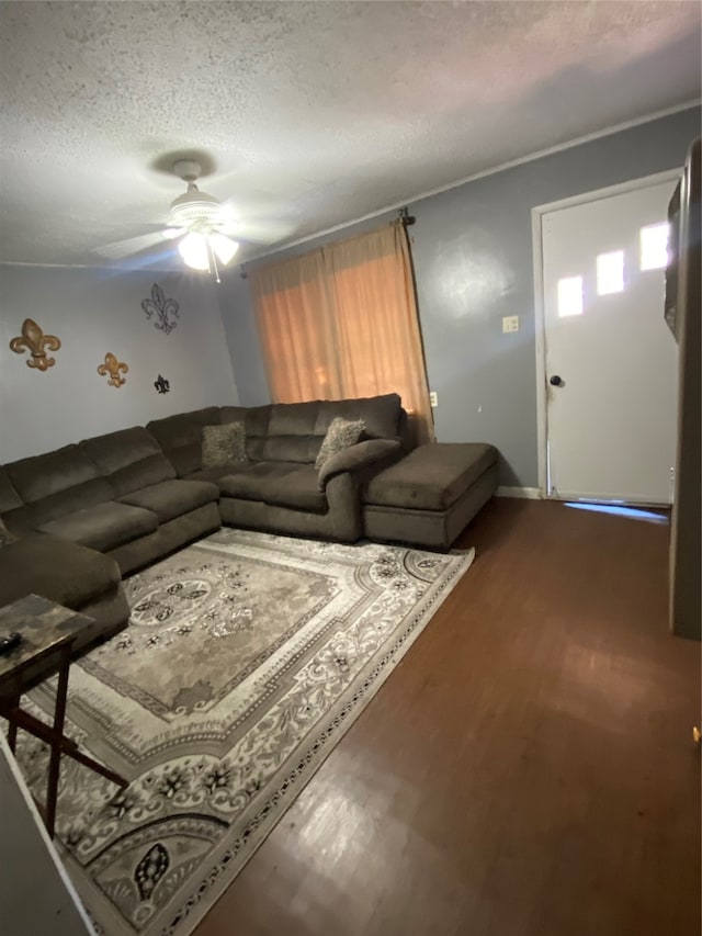 living room with dark wood-type flooring, a textured ceiling, and ceiling fan