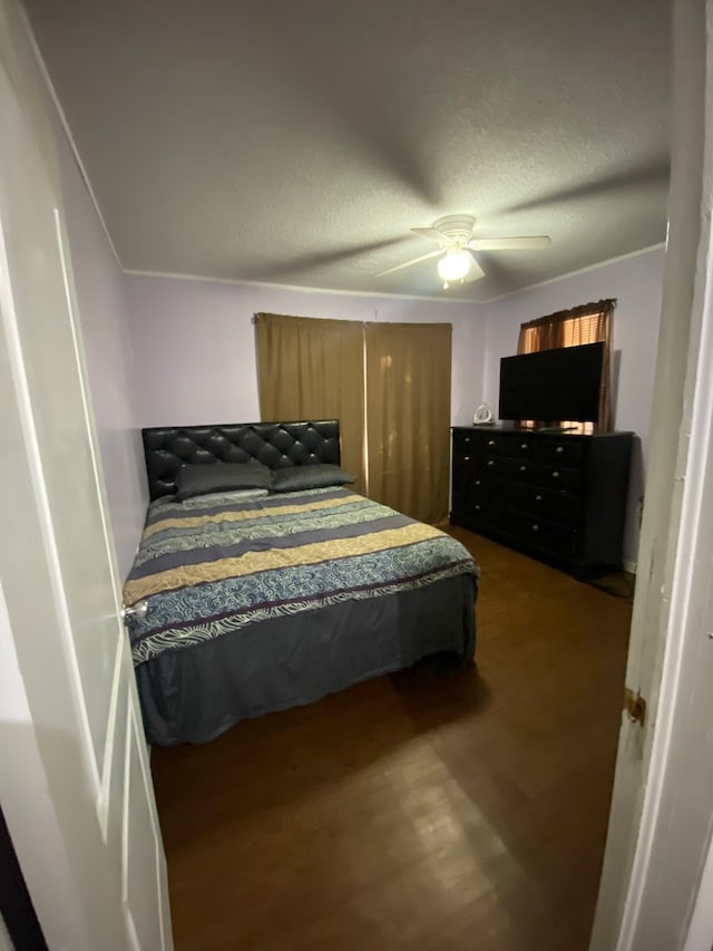 bedroom with a textured ceiling, dark hardwood / wood-style flooring, and ceiling fan