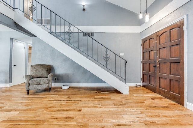 foyer entrance featuring high vaulted ceiling and light wood-type flooring