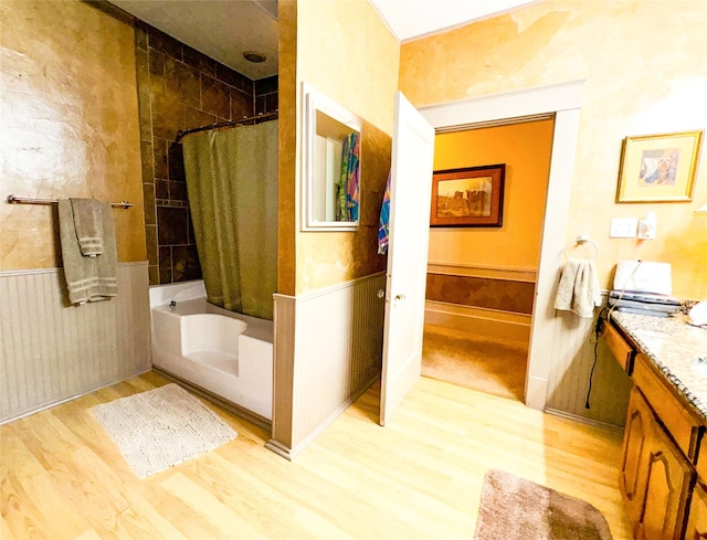 bathroom with hardwood / wood-style flooring, vanity, and shower / bathtub combination with curtain