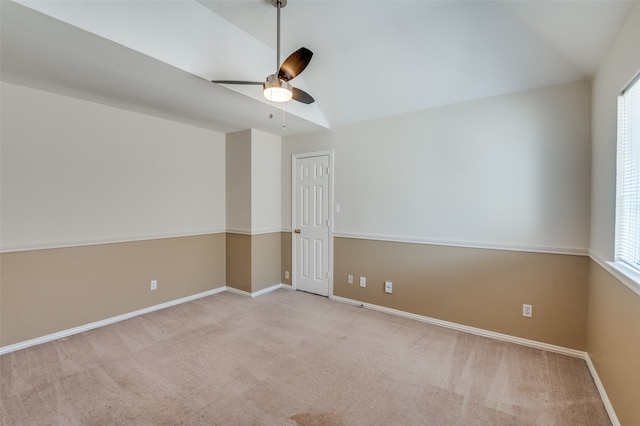 carpeted spare room with vaulted ceiling, ceiling fan, and plenty of natural light