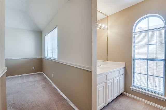 bathroom featuring a wealth of natural light, vanity, and lofted ceiling