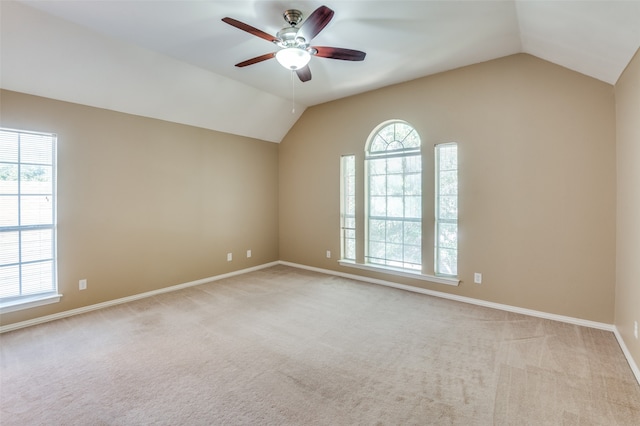 empty room with lofted ceiling, ceiling fan, and a wealth of natural light