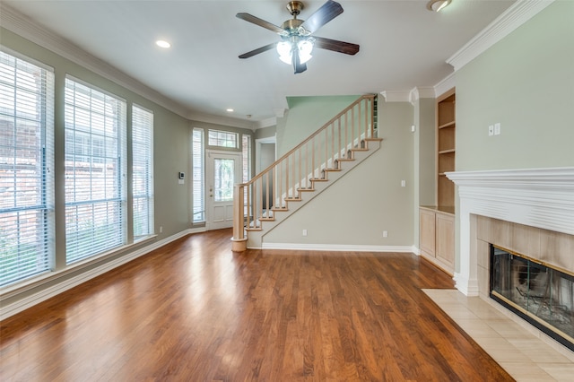 unfurnished living room featuring ornamental molding, wood-type flooring, a fireplace, and a healthy amount of sunlight