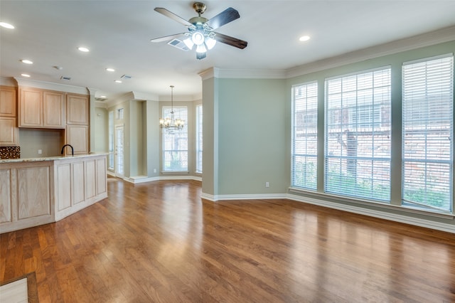 unfurnished living room with sink, crown molding, wood-type flooring, and ceiling fan with notable chandelier