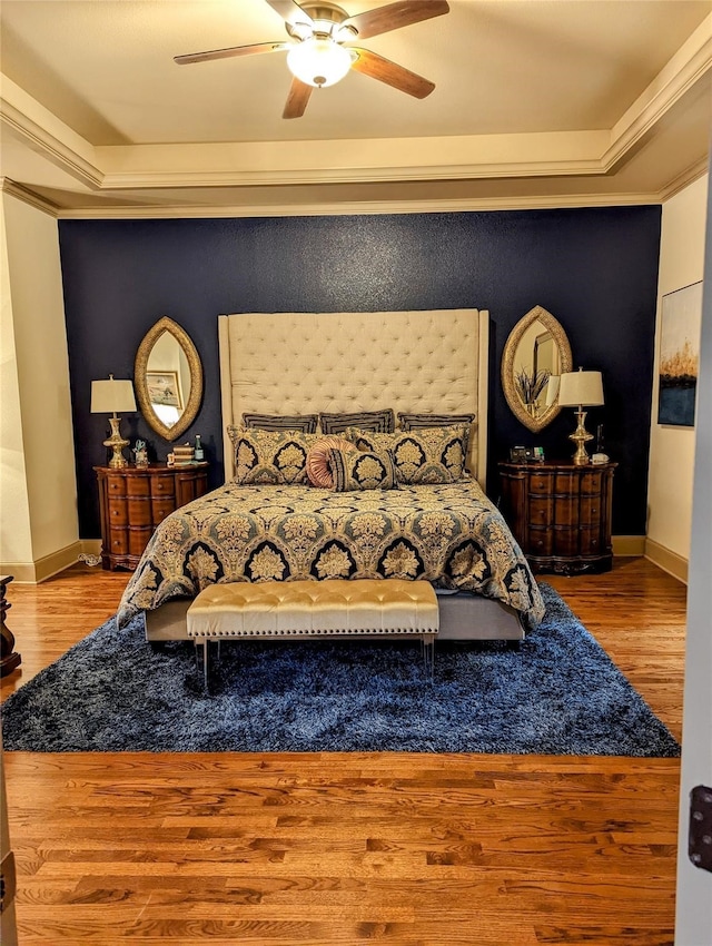 bedroom featuring ornamental molding, a tray ceiling, light hardwood / wood-style floors, and ceiling fan