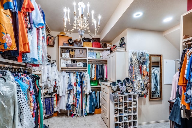 walk in closet featuring light colored carpet, a notable chandelier, and vaulted ceiling