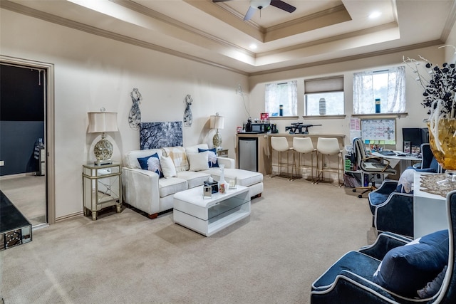 carpeted living room with ceiling fan, a tray ceiling, and ornamental molding