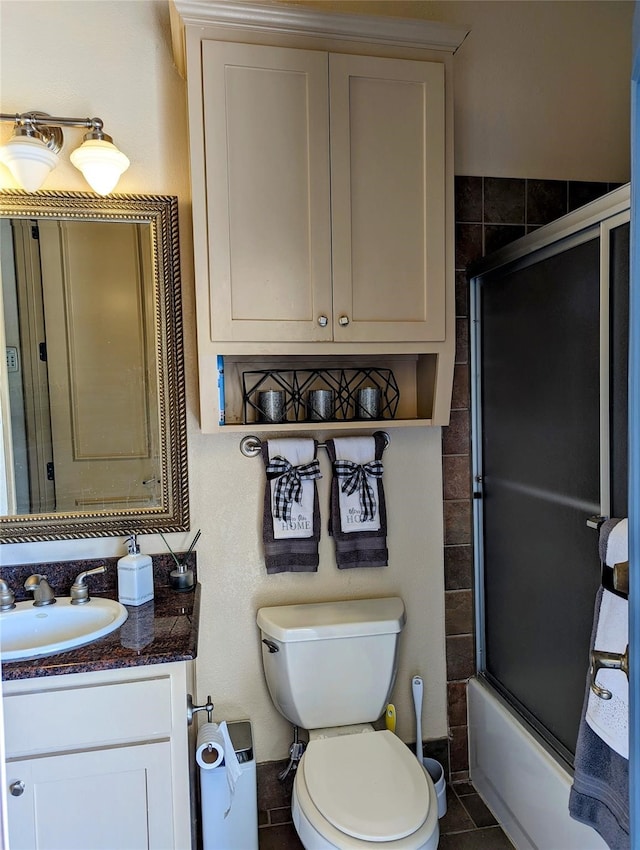 full bathroom with tile patterned flooring, vanity, toilet, and bath / shower combo with glass door