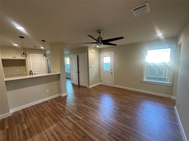 unfurnished living room with dark hardwood / wood-style flooring, sink, and ceiling fan