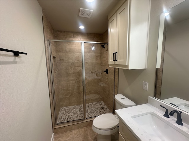 bathroom featuring a shower with door, vanity, toilet, and tile patterned flooring