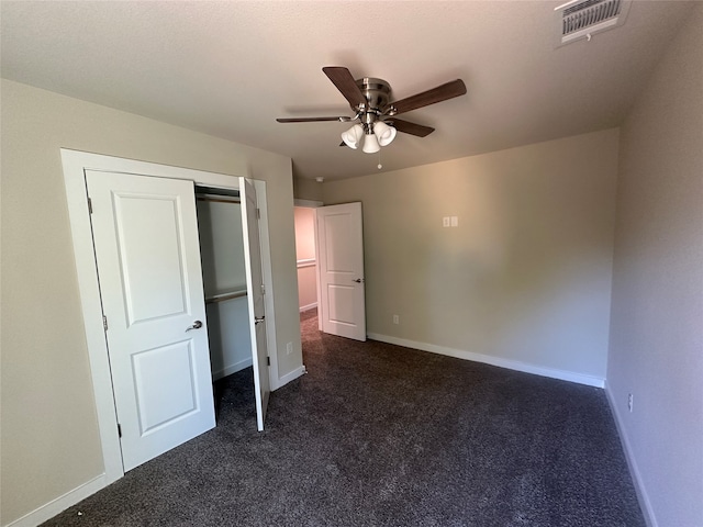 unfurnished bedroom featuring ceiling fan, dark carpet, and a closet