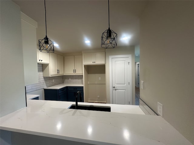 kitchen with blue cabinetry, white cabinetry, sink, and decorative light fixtures