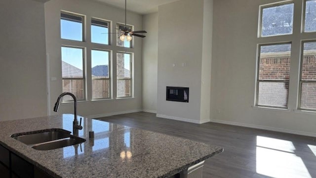 kitchen featuring sink, a mountain view, dark wood-type flooring, ceiling fan, and light stone counters