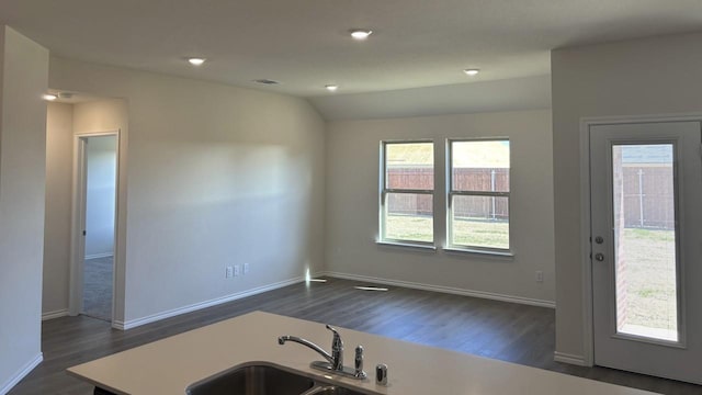 kitchen with dark wood-style floors, vaulted ceiling, light countertops, and a sink