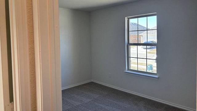 spare room with dark carpet and baseboards