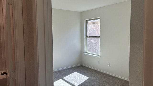 unfurnished room featuring dark colored carpet and baseboards