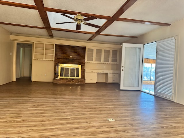 unfurnished living room with ceiling fan, coffered ceiling, a brick fireplace, light hardwood / wood-style flooring, and a textured ceiling