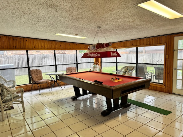 playroom featuring a wealth of natural light, wood walls, light tile patterned floors, and a textured ceiling