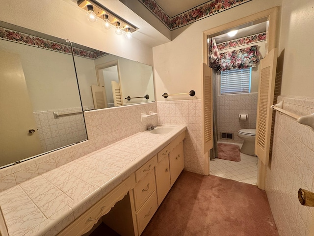 bathroom featuring tile patterned flooring, vanity, tile walls, and toilet