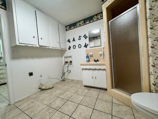 interior space with tile patterned flooring, vanity, toilet, and a shower with shower door